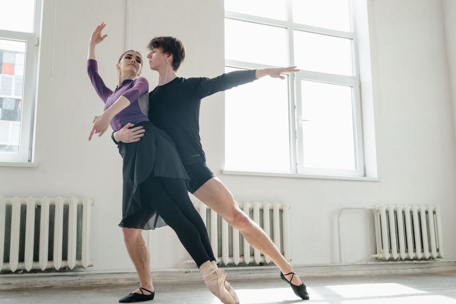 Two ballet dancers performing gracefully in a studio, practicing a duet routine.