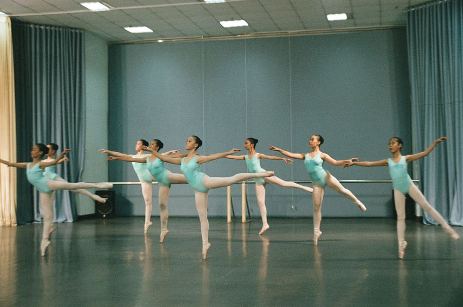 Group of young dancers practicing ballet in a studio setting with focus on grace and technique.